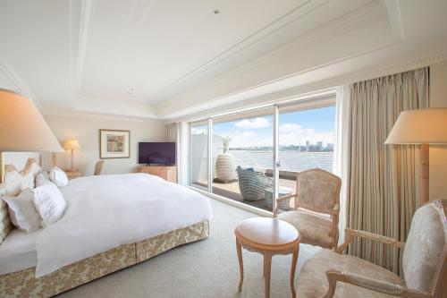 a bedroom with a large bed and a large window at Kobe Meriken Park Oriental Hotel in Kobe