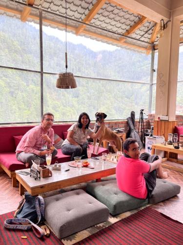 a group of people sitting around a table with a dog at ThePahadians Food & Stay in Jibhi