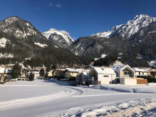 a village in the snow with mountains in the background at Urban Mountain Splitlevel with Lake View in Maurach