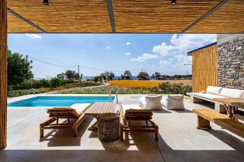 un patio con mesa, sillas y piscina en Akra Grammeno Beachfront Villas, en Palaiochóra