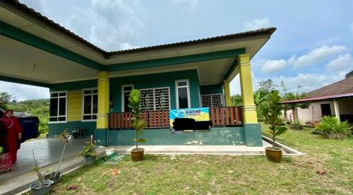 een klein huis met een groen en geel bij Sobey Laris Homestay D’ZIY AD in Merapuh