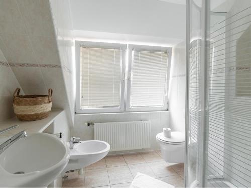 a white bathroom with a sink and a toilet at Dorpsstraat 10 in Oost-Vlieland