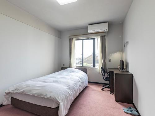 a bedroom with a bed and a desk and a window at Tabist Raika Hiroshima Miyoshi in Miyoshi