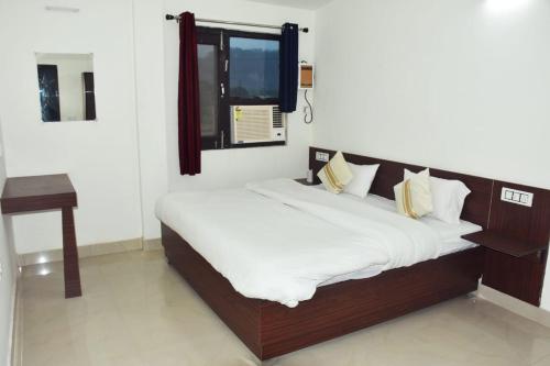 a bed with white sheets and a window in a room at Corbett Bhavesh home Stay in Jhirna