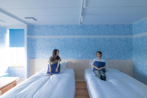 two women sitting on beds in a room at mt. inn(マウントイン） in Nihommatsu