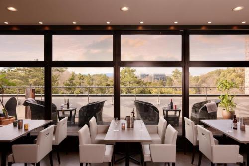 a restaurant with tables and chairs and large windows at Minamisenri Crystal Hotel in Suita