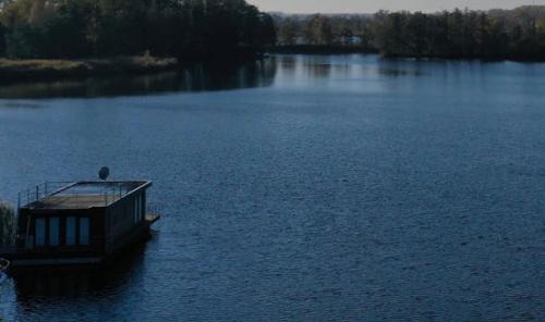 a bird sitting on a dock in the middle of a lake at Schwimmende Ferienwohnung, Hausboot Urlaub als Festlieger am Steg in Zehdenick