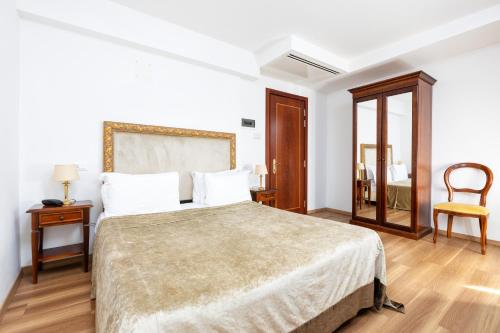 a white bedroom with a large bed and a chair at Hotel Giardinetto Venezia in Venice-Lido