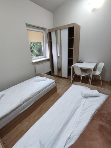 a bedroom with two beds and a table and a window at Trevena Kretinga in Kretinga