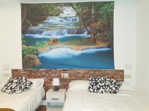 Cette chambre comprend deux lits et une peinture représentant une cascade. dans l'établissement Hotel Al-Ándalus Peal, en Cazorla Comarca, à Peal de Becerro