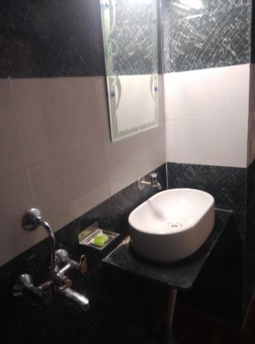 a bathroom with a white sink and a mirror at Corbett Bhavesh home Stay in Jhirna