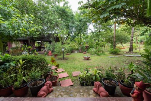 a garden with a bunch of potted plants and tables at Rosathorn Homestay San Kamphaeng in Ban Mae Pu Kha