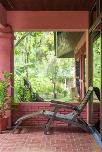 a bench sitting on the porch of a house at Rosathorn Homestay San Kamphaeng in Ban Mae Pu Kha