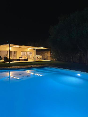 a swimming pool in front of a house at night at Villa mare Fontane Bianche in Fontane Bianche