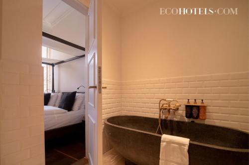 a bathroom with a large tub and a bed at Axel Guldsmeden in Copenhagen