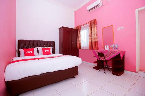 a pink bedroom with a bed and a pink desk at OYO 1847 Jasmine Kost Syariah in Jambi