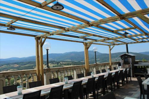 a row of tables and chairs on a balcony with mountains at Tuscan Farmhouse with 7 Apartments for max 30 persons in Montecastelli Pisano