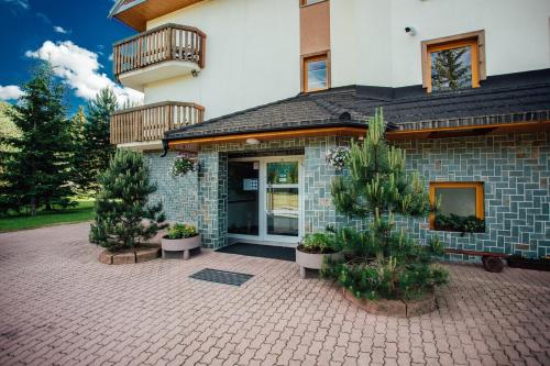 a house with two potted trees in front of it at Penzión Antares in Zuberec