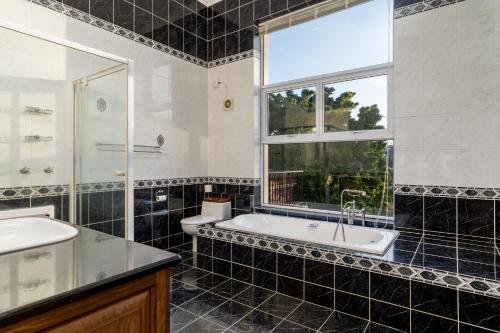 uma casa de banho com uma banheira, um lavatório e uma janela em Red Victorian Mansion em Somerset West