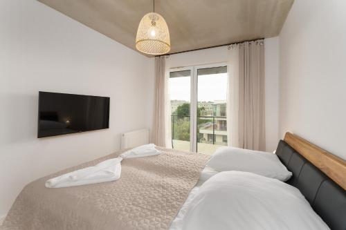 ein Schlafzimmer mit einem Bett, einem Fernseher und einem Fenster in der Unterkunft Optima na Wyspie Solnej z parkingiem in Kołobrzeg