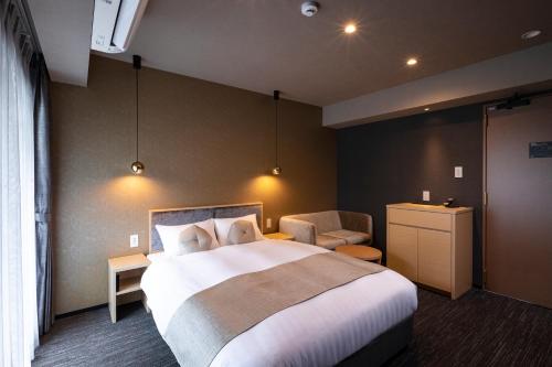 a hotel room with a large bed and a chair at Rinn Horikawa Gojo in Kyoto