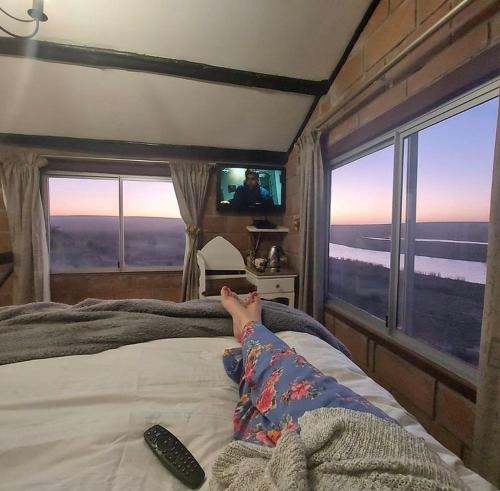 a person laying on a bed watching a television at The love bubble in Lutzville