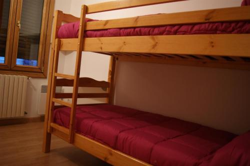 a bunk bed room with two bunk beds with red sheets at Apartamentos Borruscall in Pas de la Casa