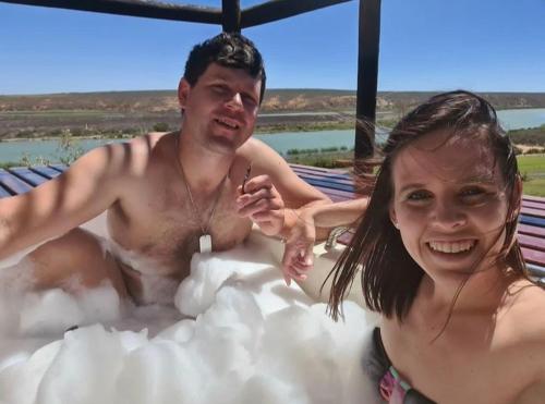 a man and a woman sitting in a hot tub at The love bubble in Lutzville