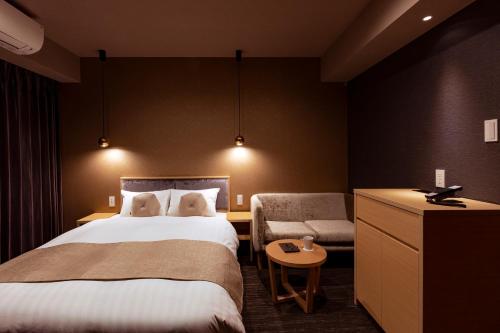 a hotel room with two beds and a chair at Rinn Horikawa Gojo in Kyoto