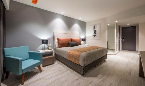 Real Inn Perinorte في مدينة ميكسيكو: غرفة نوم بسرير وكرسي ازرق