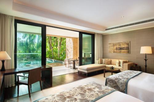 a bedroom with a bed and a desk and a couch at Raffles Hainan Clear Water Bay in Sanya