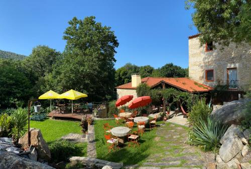 a garden with tables and umbrellas and a building at Azenha do Tio Luís in Caminha