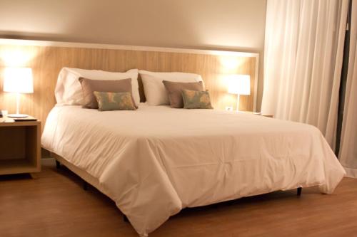 a bedroom with a large white bed with two lamps at Brizo Neuquén in Neuquén
