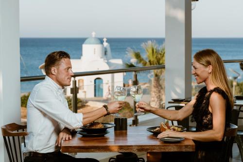 a man and woman sitting at a table with wine glasses at Golden Coast Beach Hotel in Protaras