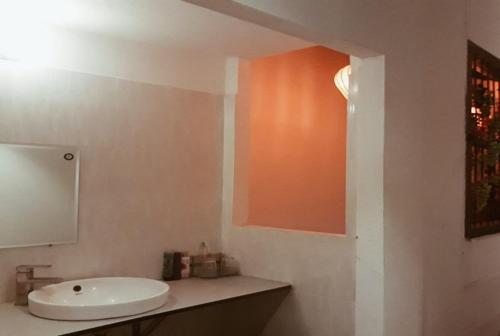 baño con lavabo blanco y pared de color naranja en Tony Central Hostel, en Luang Prabang