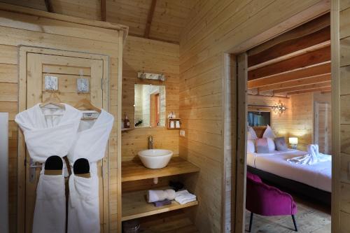 Cabaña de madera con baño con lavabo y cama en Les Lodges de Babylone, en Larringes
