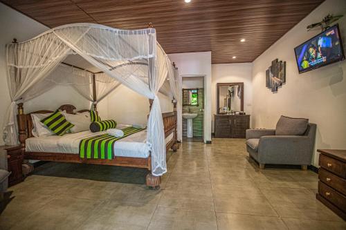 a bedroom with a canopy bed and a couch at Avenra Cottage in Ella