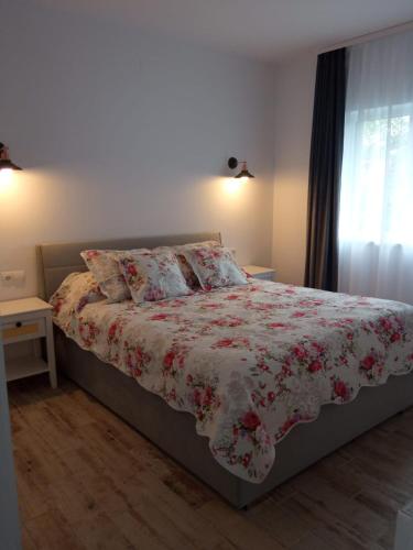 a bedroom with a bed with a floral comforter and a window at Apartament lângă Catedrală in Câmpulung Moldovenesc