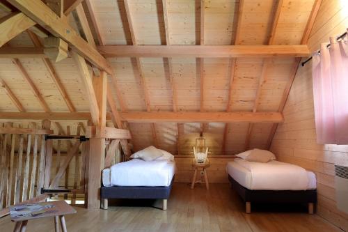 two beds in a room with wooden ceilings at Les Lodges de Babylone in Larringes