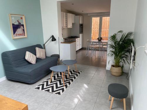 a living room with a blue couch and a kitchen at Maisonnette proche plage Saint-Malo in Saint Malo