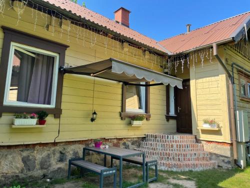 a yellow house with a table and an umbrella at Apartment near the river with it's own entrance in Līgatne