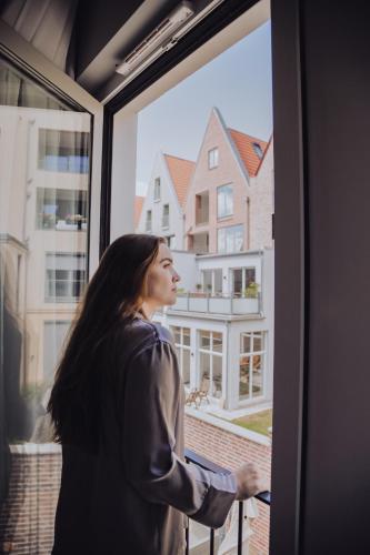 a woman looking out the window of a building at The Layhead B&B in Lübeck