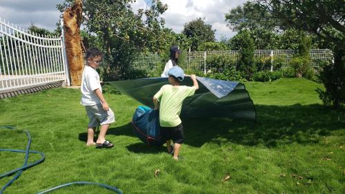 three children are playing with a kite in a yard at KAZUO Village in Bao Loc