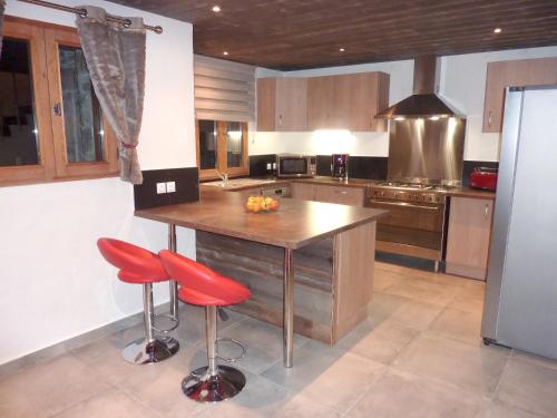 une cuisine avec un îlot en bois et des tabourets de bar rouges dans l'établissement Chalet chaleureux à Champagny-en-Vanoise avec sauna 96 m², à Champagny-en-Vanoise
