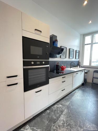 een keuken met witte kasten en een zwarte oven bij Appartement de grand standing in Saintes
