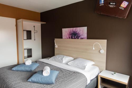 a bedroom with a bed with two blue pillows at Hotel The Happy Traveler in Groningen