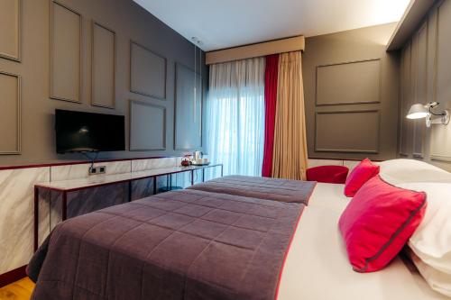 a bedroom with a large bed with red pillows at Herodion Hotel in Athens