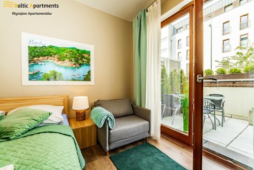 sypialnia z łóżkiem, krzesłem i oknem w obiekcie Baltic Apartments - Portofino w Świnoujściu