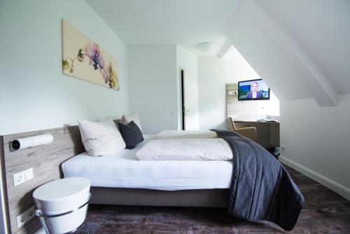 a bedroom with a white bed with a stool at Sporthotel Fuchsbachtal in Barsinghausen