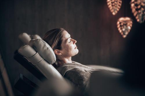 a woman sitting in a chair with her hand on her head at Hotel Alpin Spa Tuxerhof in Tux